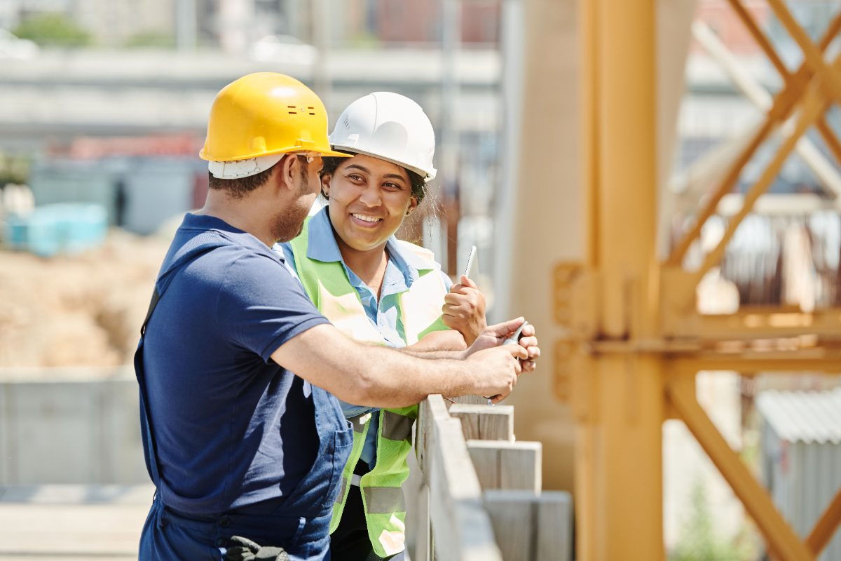 Two crew members in hard hats talking on a job site